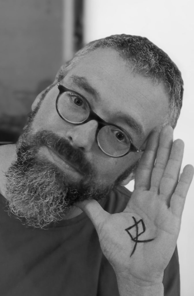 Ein Portraitbild von Herr Prof. Dr. Matten, welcher seine linke Hand neben sein Gesicht hält. Auf die Hand wurde das chinesische Schriftzeichen "Shi" geschrieben, welches für "Geschichte" steht.