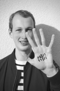 Portrait von Florian Keßler mit dem Zeichen "shu" in die Hand geschrieben